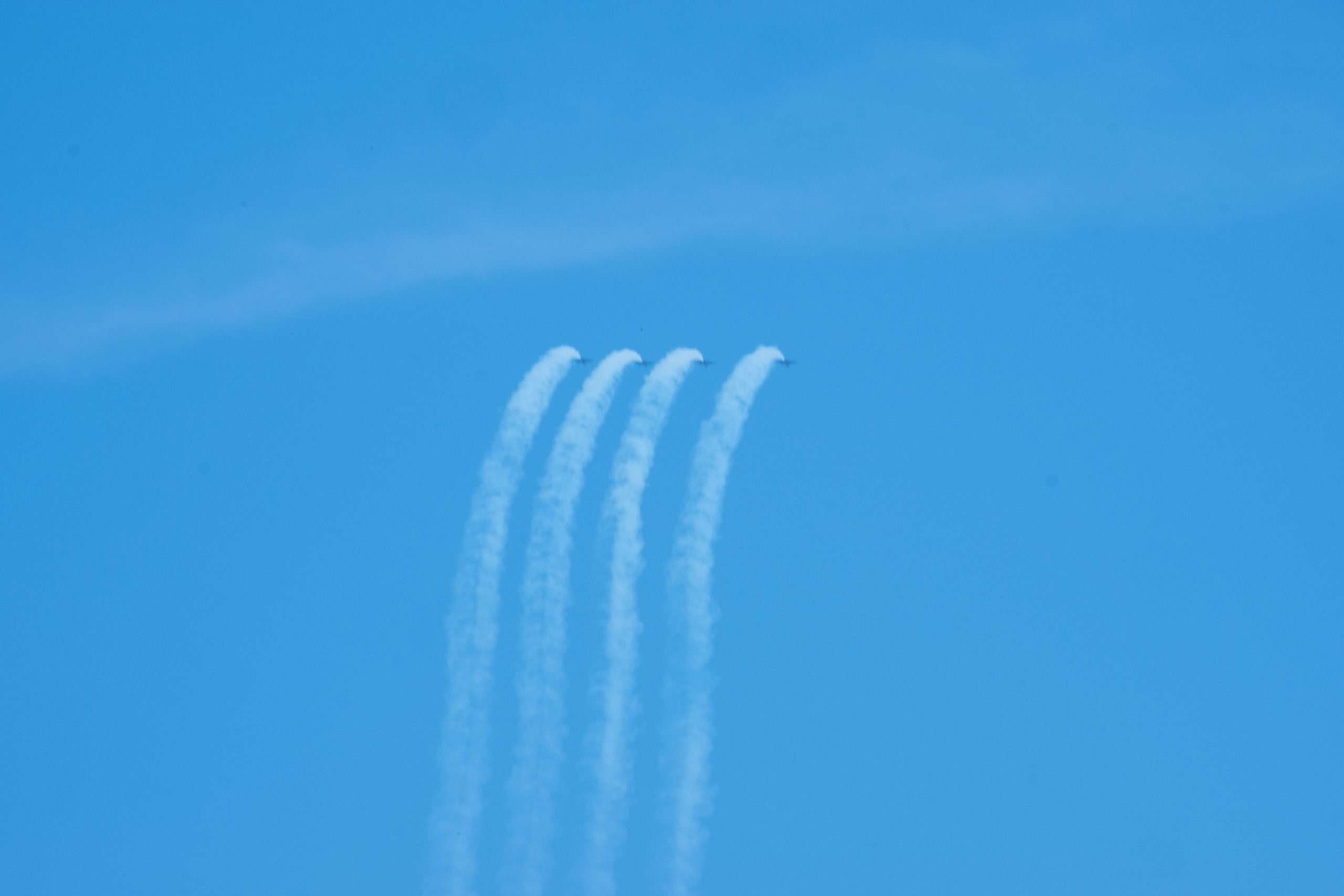 Four Blue Angels jets in side-by-side formation execute a synchronized loop.