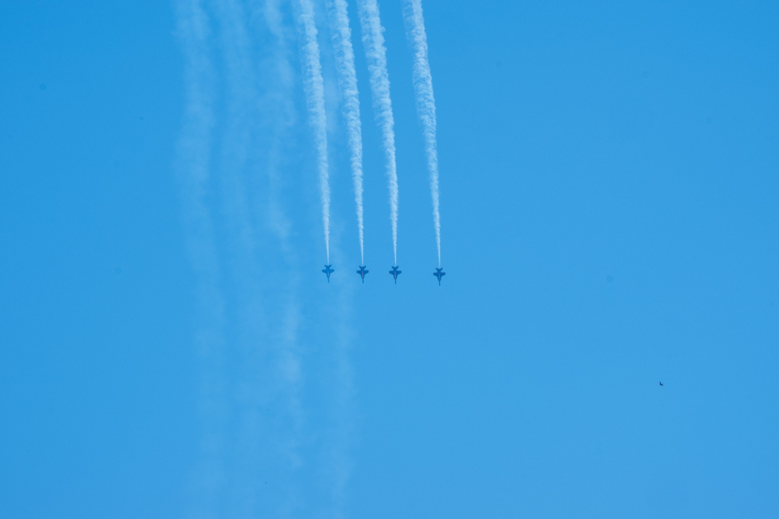 Four Blue Angels jets in side-by-side formation complete a synchronized loop.